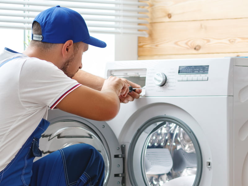 close up of an appliance repair contractor using a screwdriver while repairing a washer merlin or